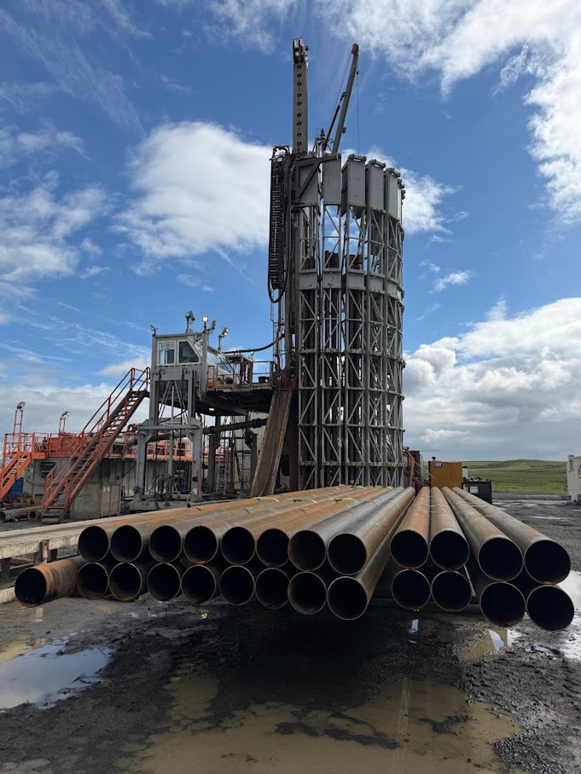 Borinn í Kaldárholti sem North Tech Drilling notaði. Í forgrunni sjást stálrör sem notuð eru í vinnslufóðringu holunnar. Vinnslufóðringin tryggir að kalt grunnvatn komist ekki inn í holuna.